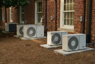 Five air conditioning units outside of red brick building